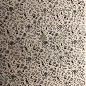 May include: Beige fabric featuring a repeating pattern of black line drawings of coffee pots, cups, flowers, pastries, and other breakfast items. A coin is in the centre of the fabric.