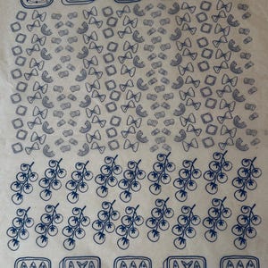 May include: A repeating pattern of blue line art illustrations on a light background. The design includes sardine cans, pasta shapes, and bunches of tomatoes. The sardine cans have the word "Sardinas" on them.