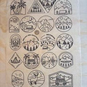 May include: Sheet of black and white camping-themed stickers. Designs include mountains, tents, palm trees, and a camper van. The stickers are arranged in various shapes, including circles, triangles, and rectangles. A 25p coin is visible for size comparison.