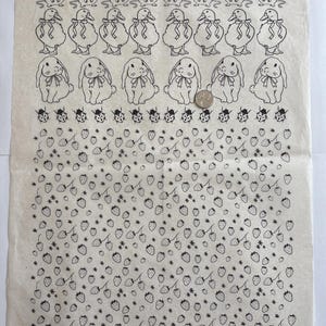 Pode incluir: Uma folha retangular de papel off-white com linhas de ilustrações em traço preto, incluindo ratos, patos com laços, coelhos com laços e joaninhas, seguidas por um padrão de morangos e pequenas flores, com uma moeda de 2,4 cm para escala.