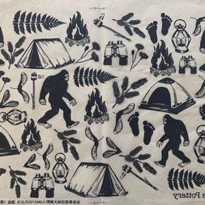 Puede incluir: Una tela estampada en blanco y negro con ilustraciones de tiendas de campaña, fogatas, huellas y Bigfoot. La tela también incluye el texto "Erica Rose Pottery".
