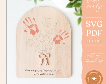 Op de afbeelding: Een digitale download van een lasergesneden ontwerp voor een houten bord met een bloemenboeket en ruimte voor maximaal vier handafdrukken. Het bord heeft de tekst "Your love gives us the strength to grow. Happy Mother's Day." en "Fits up to four hands."
