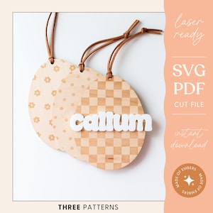 May include: Three laser-cut wooden ornaments with different patterns: floral, checkered, and polka dot. The checkered ornament has the name "Callum" written in white letters.