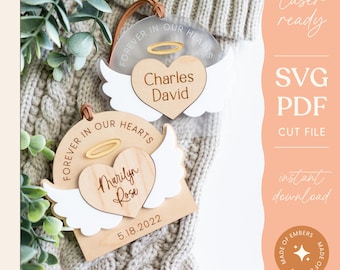 May include: Two wooden ornaments with angel wings and hearts. The top ornament says "Forever in our hearts" with the name "Charles David". The bottom ornament says "Forever in our hearts" with the name "Marilyn Rose" and the date "5.18.2022".