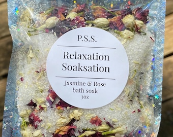 Könnte beinhalten: Ein transparenter Plastikbeutel gefüllt mit weißem Badesalz, getrockneten Rosenblüten und Jasminblüten. Der Beutel trägt ein Etikett mit der Aufschrift "P.S.S. Relaxation Soaksation Jasmine & Rose bath soak 3 oz."