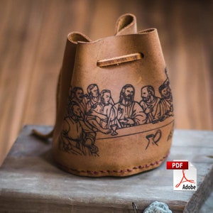 May include: A brown leather pouch with a drawstring closure. The pouch features a black and white illustration of the Last Supper.