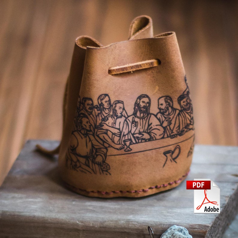 May include: A brown leather pouch with a drawstring closure. The pouch features a black and white illustration of the Last Supper.