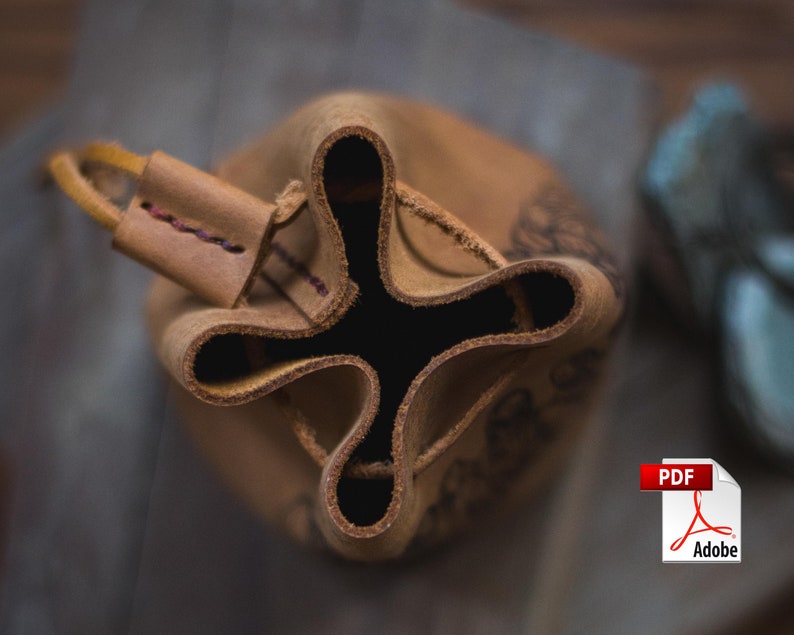 May include: A brown leather pouch with a drawstring closure. The pouch is folded in on itself, revealing the inside. The pouch has a decorative design on the outside.