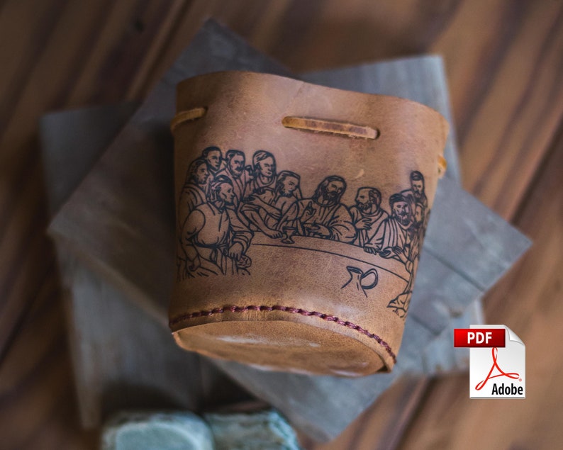 May include: A brown leather cup with a black and white illustration of the Last Supper. The cup has a red stitching detail around the top.