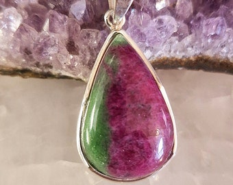 May include: A teardrop-shaped pendant with a green and pink gemstone set in sterling silver.