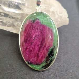 Puede incluir: Pendiente de forma ovalada con una piedra preciosa verde y rosa engastada en plata. La piedra preciosa tiene un patrón único de verde y rosa.