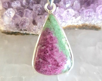 May include: A teardrop-shaped pendant with a green and pink gemstone set in silver.