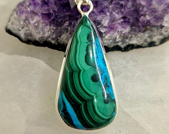 May include: A teardrop-shaped pendant featuring a green and blue malachite stone set in sterling silver.