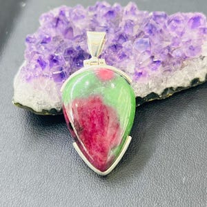 Peut inclure: Un pendentif en forme de larme avec une pierre précieuse verte et rose sertie dans de l'argent.