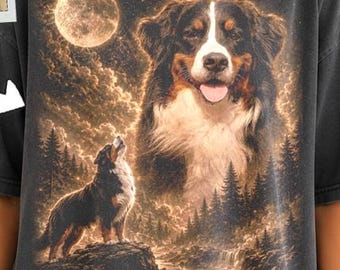 May include: A charcoal gray t-shirt featuring a large graphic print of a Bernese Mountain Dog. The design includes a smaller inset photo of the same dog breed, a full moon, a forest landscape, and a dog howling at the moon in golden tones.