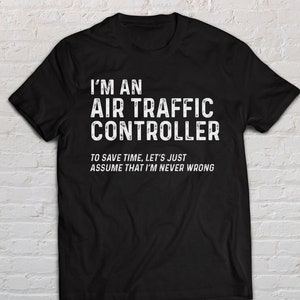 以下が含まれることがあります： 白文字の黒いTシャツ。テキストは「I'M AN AIR TRAFFIC CONTROLLER」と「TO SAVE TIME, LET'S JUST ASSUME THAT I'M NEVER WRONG」と書かれています。このシャツはクルーネックで、綿でできているようです。