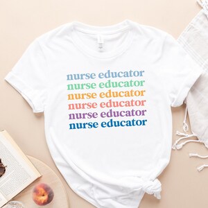 May include: White t-shirt with the text "nurse educator" repeated six times in rainbow colors.