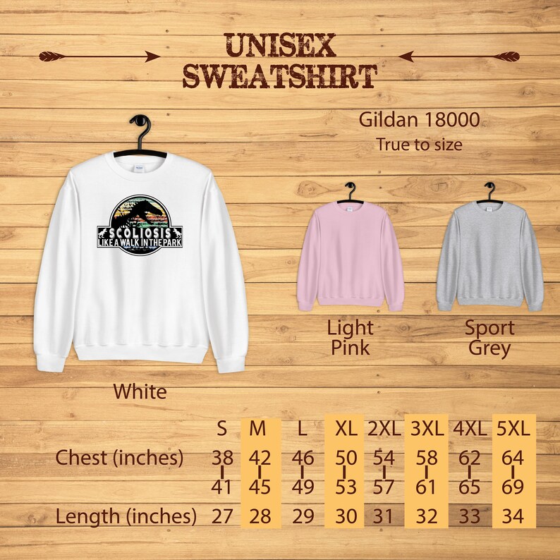 May include: White, light pink, and sport grey unisex sweatshirt with the text "Scoliosis Like A Walk In The Park" and a dinosaur graphic. Size chart with chest and length measurements in inches.