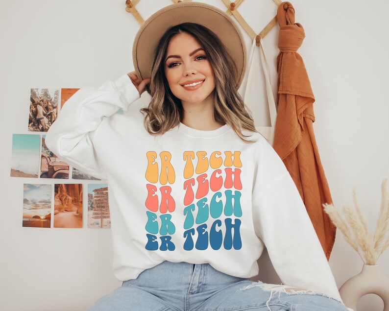 Op de afbeelding: Wit sweatshirt met een kleurrijk retro-ontwerp met de tekst "ER TECH" die vier keer wordt herhaald.