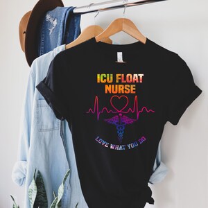 May include: Black t-shirt with the text "ICU FLOAT NURSE" in a rainbow gradient. Below the text is a heart-shaped EKG line, a medical symbol, and the words "LOVE WHAT YOU DO."