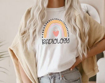May include: A white t-shirt with a rainbow graphic and the text "RADIOLOGY" in black. The rainbow has a pink heart in the center.