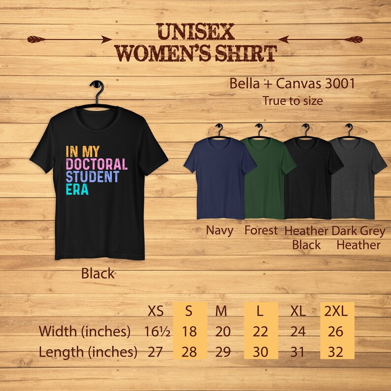 May include: Black, navy, forest green, and heather dark grey t-shirt with the text "In My Doctoral Student Era" in colorful letters. The shirt is available in sizes XS to 2XL. The size chart shows the width and length in inches.