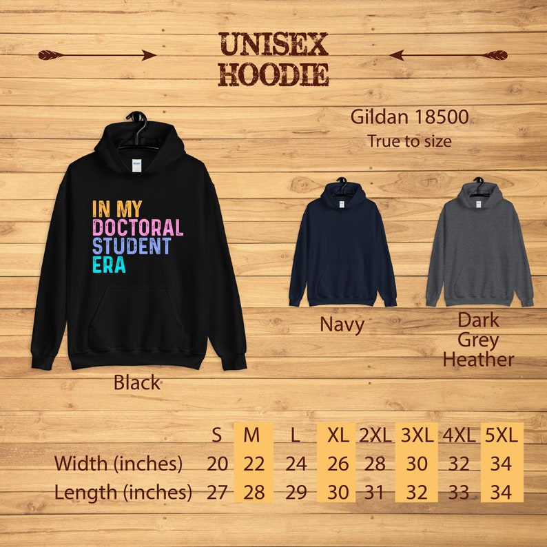 May include: Unisex hoodie with the text "In My Doctoral Student Era" in rainbow colors. The hoodie is available in black, navy, and dark grey heather. Size chart shows width and length in inches.