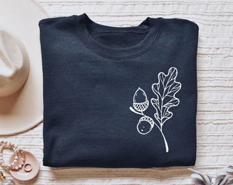 May include: A dark blue sweatshirt with a white outline of an oak leaf and acorns.