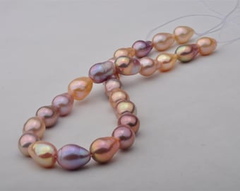 May include: A strand of iridescent pink and peach freshwater pearls strung on a white cord. The pearls are teardrop shaped and have a natural, organic look.