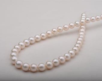 May include: A strand of lustrous, off-white pearls, arranged in a looping pattern. The pearls are round and evenly sized, with a subtle sheen. The background is a plain, light-colored surface, highlighting the jewelry.