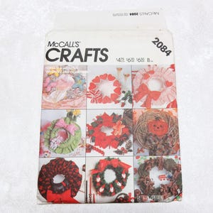 May include: A McCall's Crafts pattern envelope featuring various wreath designs. The envelope displays the McCall's logo and the number 2084. The designs include wreaths with hearts, bows, and seasonal elements.