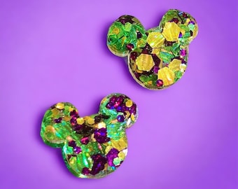 Puede incluir: Dos orejas de Mickey Mouse de resina verde, dorada y morada con purpurina.
