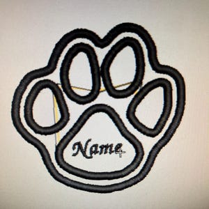 May include: Black embroidered paw print design with the word "Name" in a cursive font. The paw print has a double outline, creating a three-dimensional effect. The design is likely for pet-related items.
