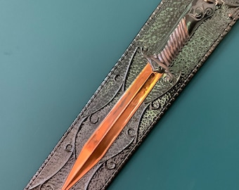 May include: A dagger with a bright copper-colored blade and a metallic silver-toned handle featuring a twisted design. The dagger is housed in a rectangular, dark silver-toned sheath with a textured surface and decorative swirling metal filigree.
