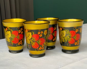 May include: Set of four traditional Russian nesting dolls, or matryoshka dolls, painted with a black, gold, and red floral design. The dolls are all different sizes and are nested inside each other.