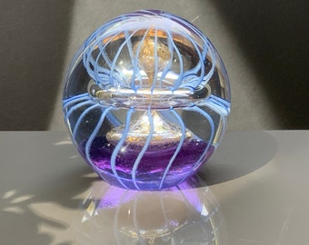 Grazioso fermacarte in vetro con un ornamento dorato al centro e strisce blu e una base in vetro viola. Decoro in vetro fermacarte