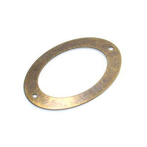 May include: A brass oval-shaped metal charm with two holes. The charm has a textured surface.