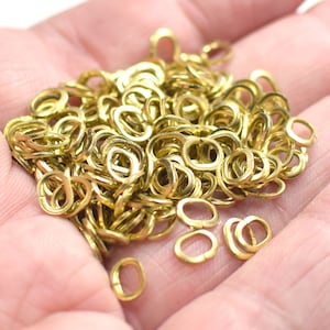 Könnte beinhalten: Ein großer Haufen goldfarbener Metall-Sprünge. Die Ringe sind oval geformt und alle gleich groß.