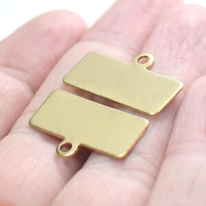 May include: Two gold-colored metal rectangular tags with a hole at the top for attaching a string or ribbon.