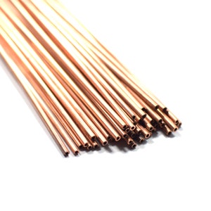 May include: A bundle of thin, copper tubing with a smooth, shiny finish. The tubing is arranged in a fan shape, with the ends of the tubes aligned. The tubes are all the same size and have a small hole at one end.