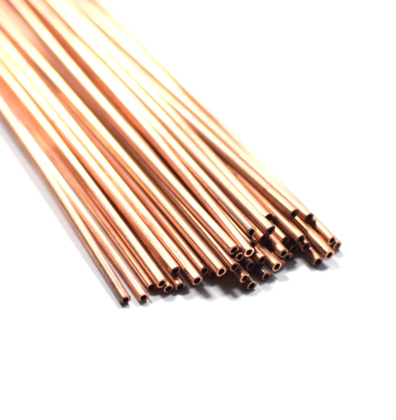 May include: A bundle of thin, copper tubing with a smooth, shiny finish. The tubing is arranged in a fan shape, with the ends of the tubes aligned. The tubes are all the same size and have a small hole at one end.