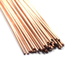 May include: A bundle of copper tubing, arranged in a fan shape, with the ends of the tubes cut at an angle. The tubes are a shiny, reddish-brown color.