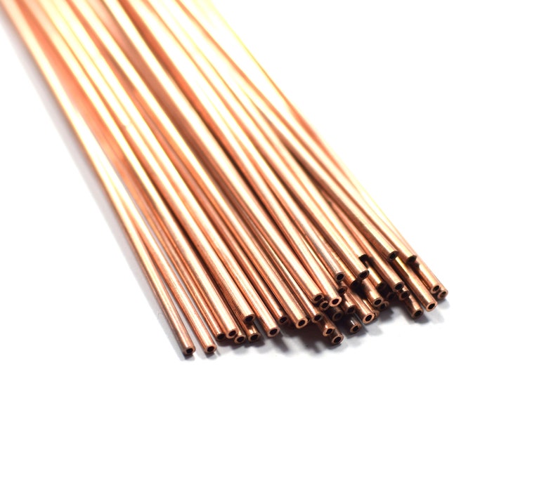 May include: A bundle of copper tubing, arranged in a fan shape, with the ends of the tubes cut at an angle. The tubes are a shiny, reddish-brown color.