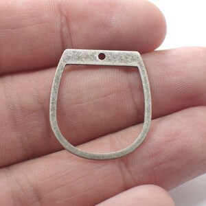 May include: Silver-toned metal charm shaped like a horseshoe with a small hole at the top.