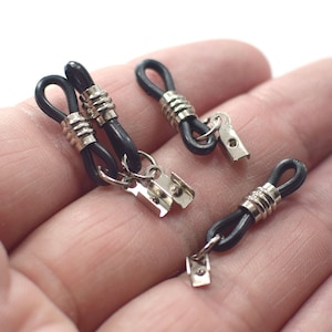 May include: Three black elastic eyeglass strap holders with silver metal clasps. The straps have a textured design.