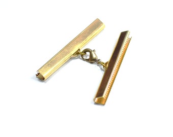 May include: Gold metal clasp with a decorative edge and a connecting chain. The clasp is used for attaching straps or cords to bags, purses, or other items.