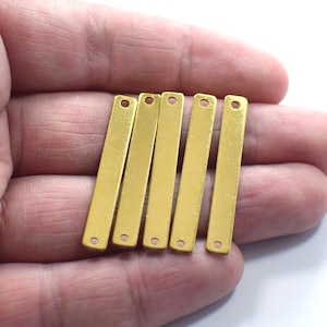 May include: Six gold-colored metal bar pendants with two holes each. The bars are flat and rectangular.
