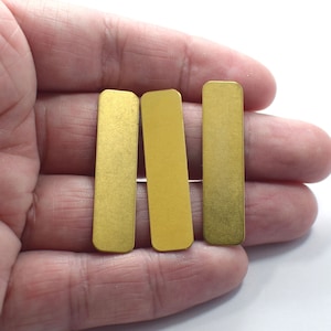 Può includere: Tre etichette rettangolari in metallo color oro. Le etichette sono lisce e hanno una superficie leggermente testurizzata.