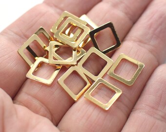May include: A pile of gold-colored metal square jump rings. The rings are open and have a smooth finish.