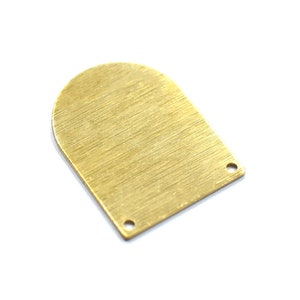 Op de afbeelding: Een gouden metalen bedel in de vorm van een boog met twee gaten. De bedel heeft een geborstelde afwerking.